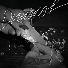 Uma imagem a preto e branco, em que são mostradas duas mãos ao centro a segurarem uma mortalha com vários diamantes em cima, entre outros que estão espalhados em cima de uma mesa onde os membros superiores estão apoiados. O nome "Diamonds" está de forma estilizada e apresentada na parte superior da fotografia, e no canto inferior direito é apresentado o logótipo "R" de uso proeminente pela cantora.