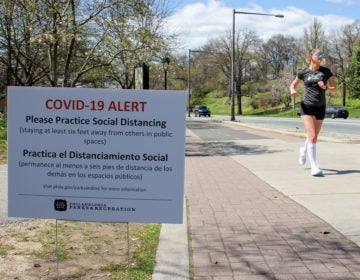 Signs posted along Philadelphia's Schuylkill River Trail caution users to keep six feet away from others to prevent the spread of COVID-19. (Emma Lee/WHYY)