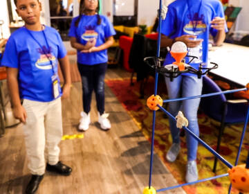 Three students flying a drone in a classroom