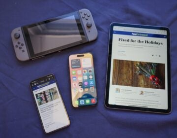 two phones, a tablet and a gaming device on a table