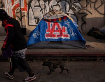 FILE - A man walks past a homeless encampment in downtown Los Angeles, Wednesday, Oct. 25, 2023. (AP Photo/Jae C. Hong, File)