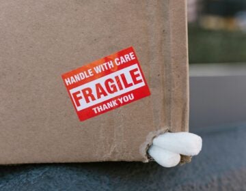 A cardboard box with packing peanuts poking out and a sticker reading HANDLE WITH CARE FRAGILE THANK YOU