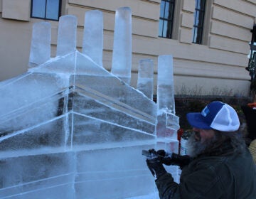 Roger Wing carves an ice sculpture of The Battery in a live ice sculpting demonstrations at the 6th annual Fishtown Freeze event on Dec. 14, 2024. (Emily Neil/WHYY)