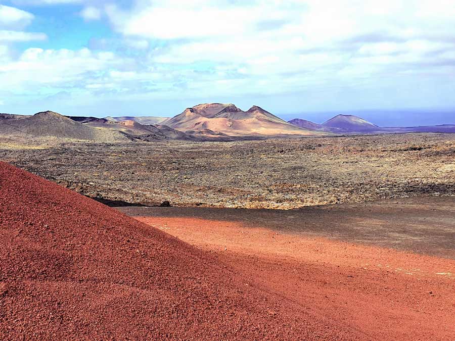 Lanzarote im Januar Erfahrungen Wetter: Ein Mix aus Wolken und Sonnenschein über der orange leuchtenden Vulkanlandschaft