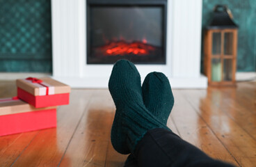 Naklejka premium woman wearing wool socks in front of fireplace