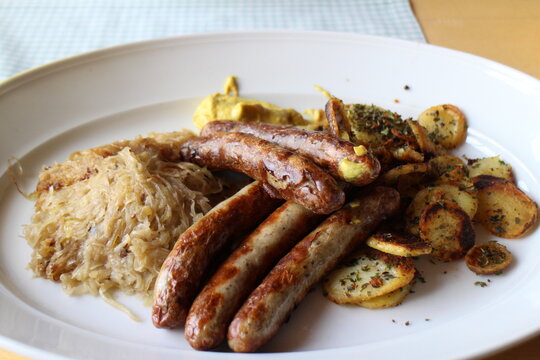 German cuisine: bratwurst (grilled pork sausages), baked potatoes and sauerkraut (sour cabbage) in Würzburg, Germany