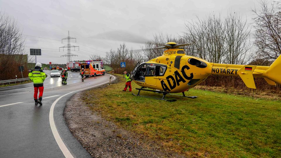 Ein Rettungshubschrauber steht auf einer Wiese neben einer Autobahnauffahrt.