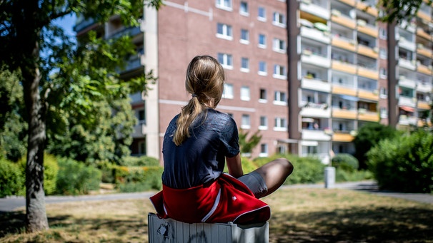 Ein Mädchen sitzt vor einem Plattenbau in Leipzig-Gruenau. Die Zahl einsamer Menschen in Deutschland steigt, besonders unter Jugendlichen und jungen Erwachsenen. Einsamkeit kann krank machen. Was könnt ihr dagegen tun? | Bild: picture alliance / ZB | Thomas Eisenhuth