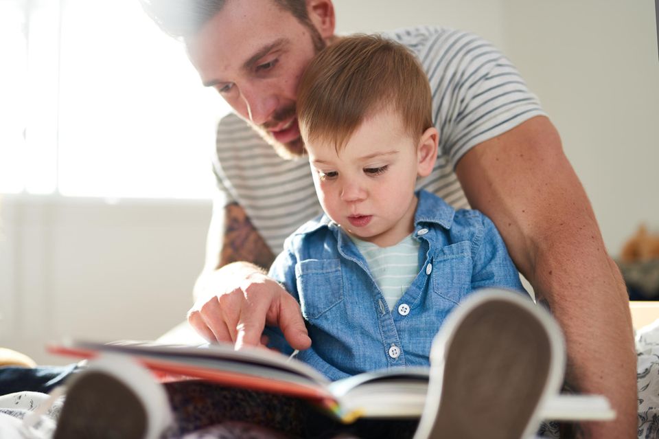 Kinderbücher zur Kita-Eingewöhnung: Junger Vater liest Kinderbuch mit Kleinkind