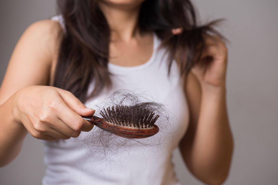 Frau zeigt ihre Bürste mit ausgefallenen Haaren