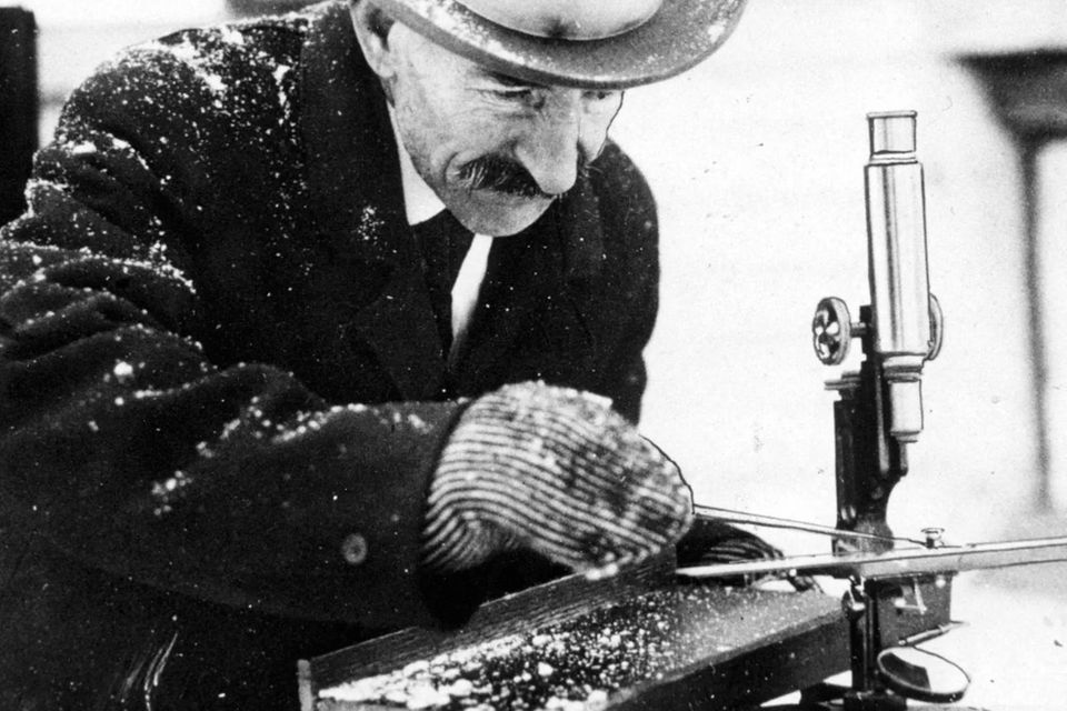 Wilson Bentley mit Hut, Mantel und Handschuhen draußen beim Schneeflocken-Fotografieren