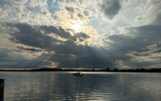 Zon schijnt door de wolken boven een zeilboot op de Schlei in Sleeswijk-Holstein, Duitsland