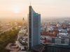 Blick auf die Skyline von Leipzig und das City-Hochhaus, während die Sonne am Horizont untergeht.