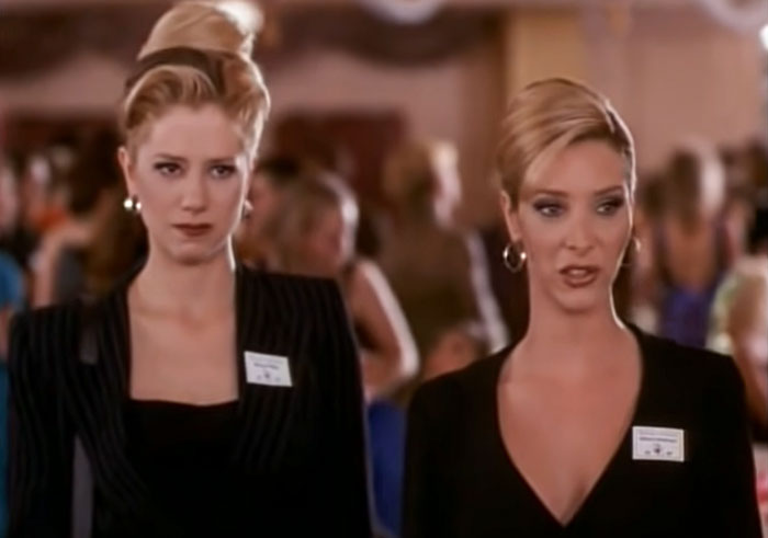 Romy and Michele in black dresses explaining something