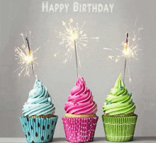 three cupcakes with sparklers on top of them and the words `` happy birthday '' .