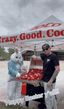 a man in a bunny costume is standing next to a man in a black shirt under a crazy good coco tent