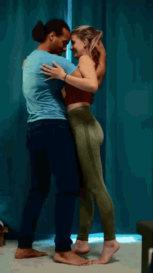 a man and a woman are hugging each other in front of a blue curtain .