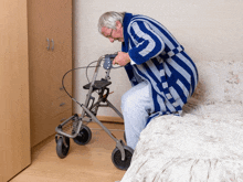 an elderly man in a blue and white robe is sitting on a bed with a walker