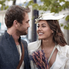 a man and a woman are looking at each other and the woman is holding a bouquet of dried flowers .