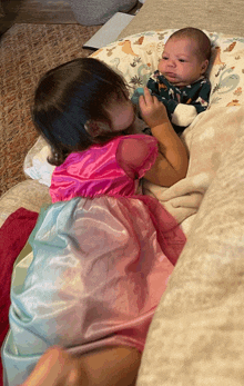 a little girl in a princess dress holds a baby