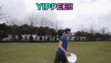 a man in a blue shirt is holding a frisbee in a field with the words yippee written on the top