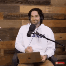 a man wearing headphones is sitting in front of a microphone and using a laptop