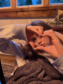 a person laying on a blanket making a heart shape with their hands