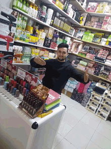 a man stands in front of a display of nail polish and a sign that says ' nails ' on it