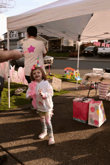 a little girl is standing in front of a tent with a sign that says " hot cotton candy "