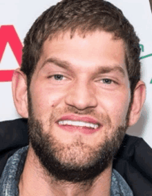 a close up of a man 's face with a beard and a smile .