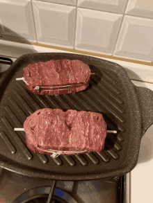 two steaks are cooking on a grill pan on a stove