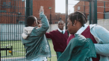 a group of people giving each other a high five in front of a fence that has the word blue on it