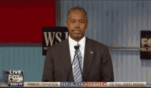 a man in a suit and tie stands in front of a microphone in front of a wall street journal banner