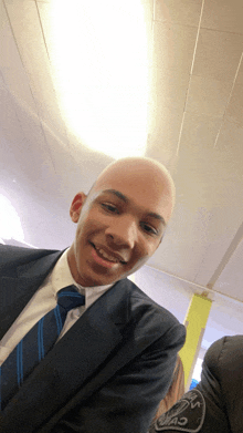 a bald man in a suit and tie is smiling for the camera