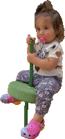 a little girl with a pacifier in her mouth sits on a green rope swing