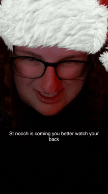 a woman wearing glasses and a santa hat has a caption that says st nooch is coming you better watch your back