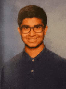 a young man wearing glasses and a blue shirt is smiling