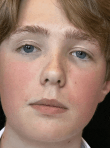 a close up of a young man 's face with blue eyes