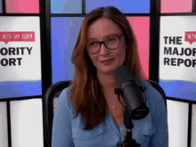 a woman is sitting in front of a microphone in front of a sign that says " the major report "