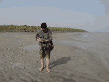 a man standing on a sandy beach looking at his cell phone