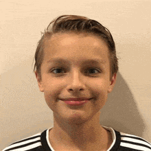 a young boy is smiling and wearing a black and white striped shirt .