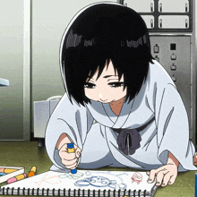 a girl in a white robe is drawing on a piece of paper with a marker