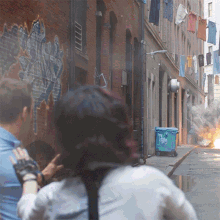 a man and a woman are walking down a street with graffiti on a wall that says ' a ' on it