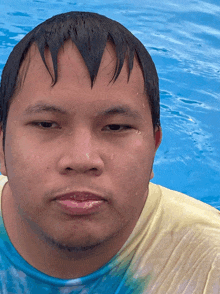 a man with wet hair and a yellow shirt is standing in the water