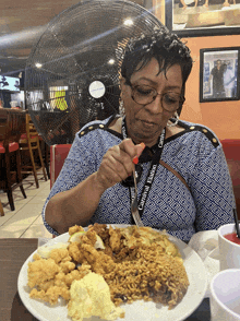 a woman wearing a lanyard that says carnival reunion eating a plate of food