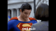 a man in a superman costume talks to a woman and says oké blc