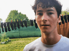 a young man stands in front of a row of socks hanging on a line