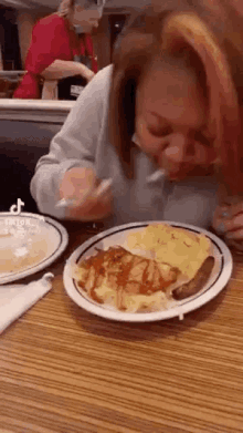 a woman is eating a plate of food at a diner with a fork .