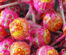 a bunch of pink and orange chupa chups are sitting on top of each other .