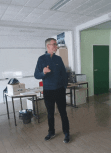 a man in a blue jacket stands in a room with a green door